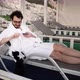 Young Caucasian Bearded Man is Resting in Lounge Area Lying on Sunbed and Playing with a Cat - VideoHive Item for Sale