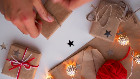 Woman Is Wrapping Present Box with Craft Paper and Red Paper Clip. Christmas and New Year Background alt