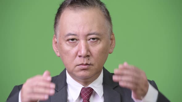 Mature Japanese Businessman Covering Ears As Three Wise Monkeys Concept alt