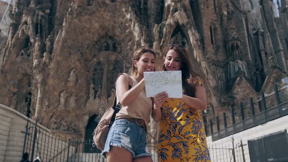 Female tourists with map at Sagrada Familia, Barcelona, Spain alt