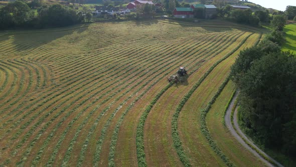 Tractor With Grass Turner At Work On Farm In Norway. Silage Production. aerial alt