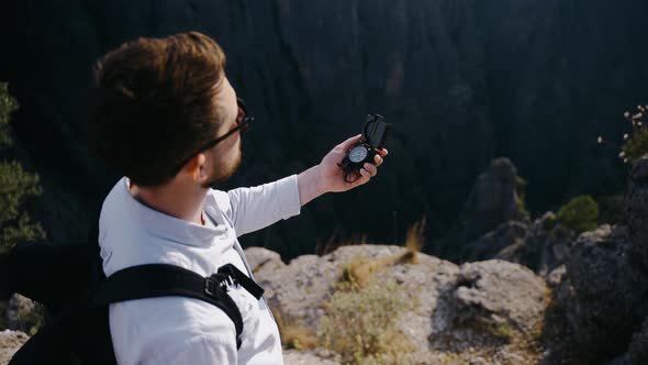 A Traveler in Sunglasses Stands on the Top of Mountain and Looks at the Compass alt