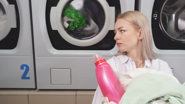 A Woman in a Public Laundry Waits for Her Laundry to Be Washed alt