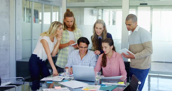 Colleagues discussing over laptop at table alt