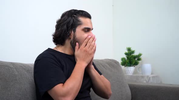 Tired and sleepy Indian man sitting on the sofa alt