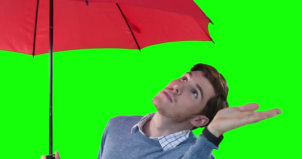 Caucasian man with an umbrella raising hand on green background
