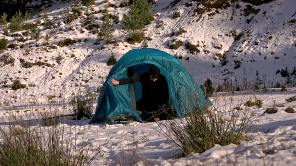 Hiker, arriving at tent, in the winter mountains alt