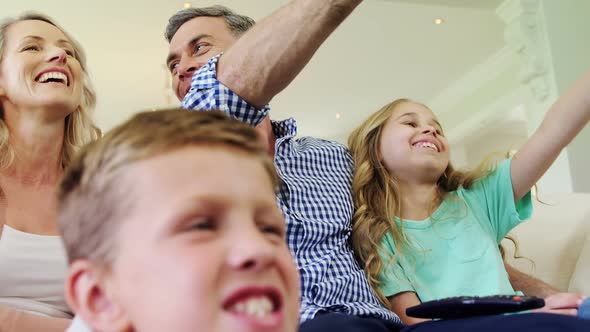 Happy family watching television together in living room alt