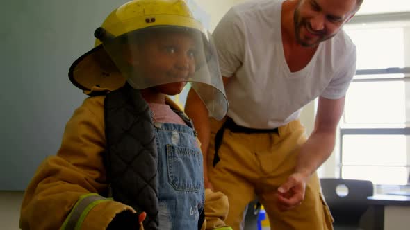 African American schoolgirl wearing firefighter uniform and raising both hands in the air while Cauc alt