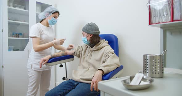 Nurse Wearing Protective Gloves and a Protective Mask Gives a Vaccine Injection