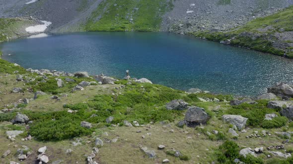 Aerial view. Woman standing near mountain emerald lake raising hands up Arkhyz North Caucasus nature alt