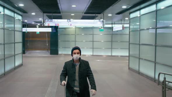 Coronavirus Pandemic Travel Bans: Man in Mask Walks with Suitcase in Airport