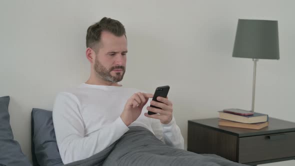 Man Reacting to Loss on Smartphone in Bed by Stockland | VideoHive