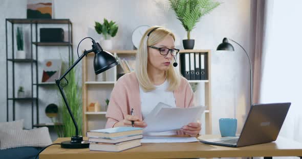 Businesswoman in Headset Sitting in front of Laptop in Cozy Home Office During Video Meeting alt