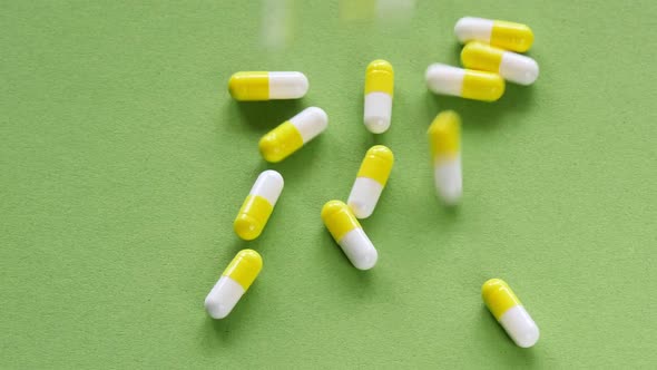 The pills are scattered on the table. Tablets on the green background