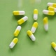 The pills are scattered on the table. Tablets on the green background