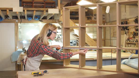 Awesome Carpenter Woman Measuring Wooden Shelf with Tape-line alt