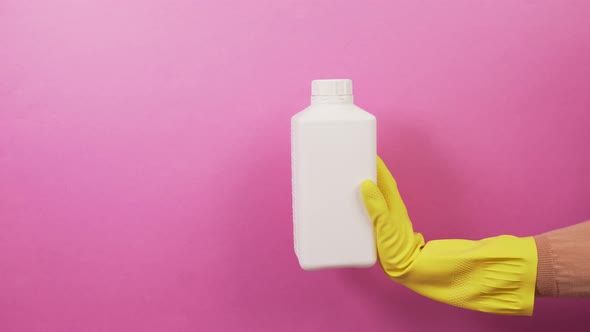 A Hand in a Yellow Rubber Glove with a Square White Jar of Household Chemicals