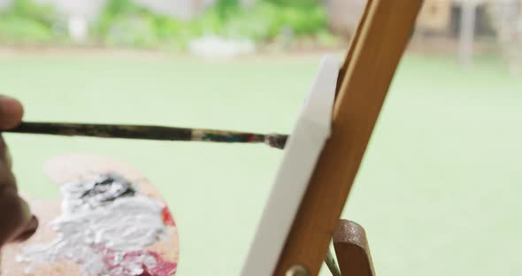 Video of african american senior man painting picture outside alt