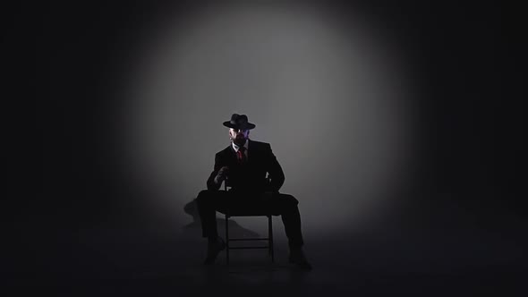 Elegant Man in a Black Hat Is Dancing an Erotic Dance. Spotlight on a Black Background. Close Up alt