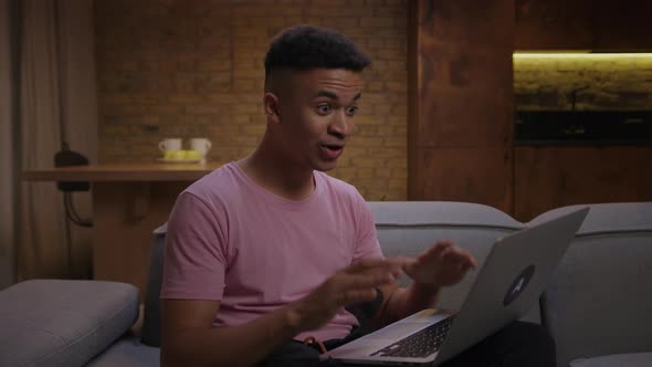 Young Adult African American Man Got Very Excited Reading a Good News on Laptop Working at Home