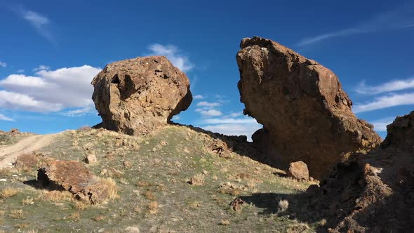 Aerial flying up and through gap between boulders in the desert alt