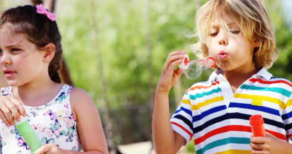 Schoolkids playing with bubble wand in playground alt