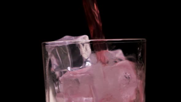 A Red Liquid is Poured Into a Clear Glass Glass with Ice alt