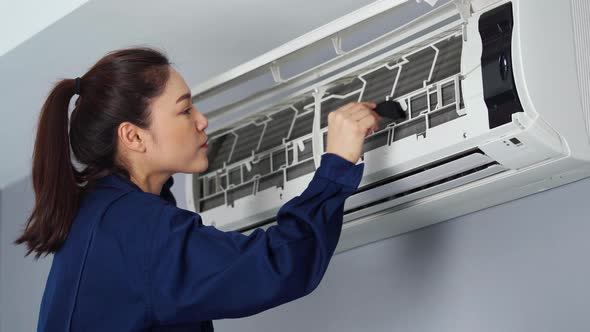technician service using brush to cleaning the air conditioner indoors