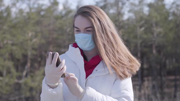 Portrait of Brunette Young Woman in Face Mask and Protective Gloves Talking on the Phone. Brunette alt