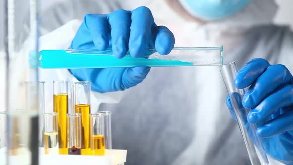 scientist working with chemical reagents and solutions pours liquid in test tube alt