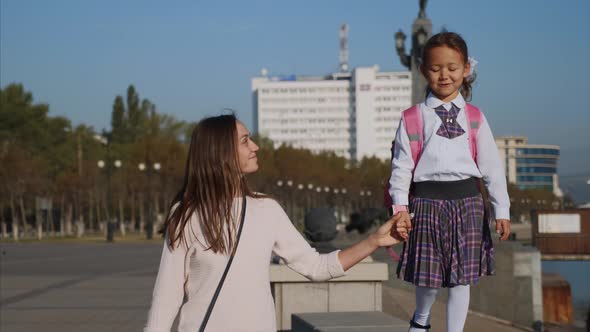 School Girl Is Walking on Railing of Seafront with Mom, Steadicam, Front View.