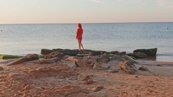 Lonely Woman in the Red T-shirt Is Standing on Stones at the Shore She Waiting for Sunrise alt