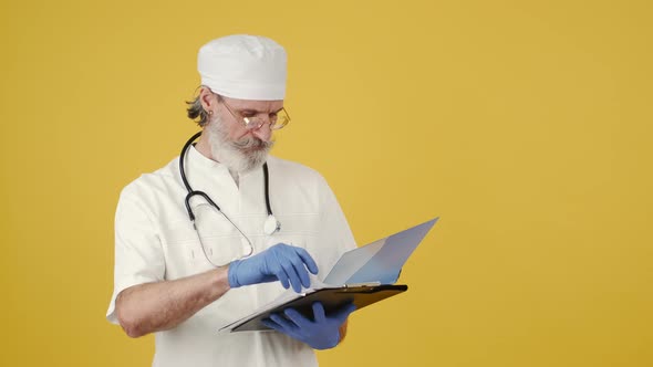 Senior Doctor with Notepad on Yellow Background alt