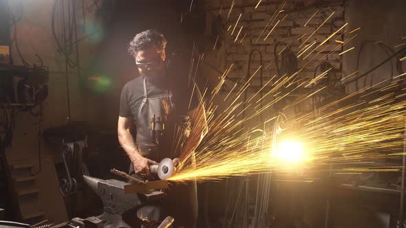 Man Working the Angle Grinder in Workshop. Blacksmith Working with Metal alt