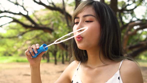 Young South East Asian 20s Woman Blowing Air Bubbles in Park alt