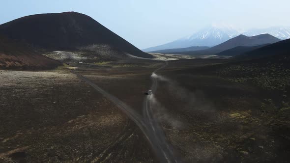 cars drive on black earth overlooking volcanoes