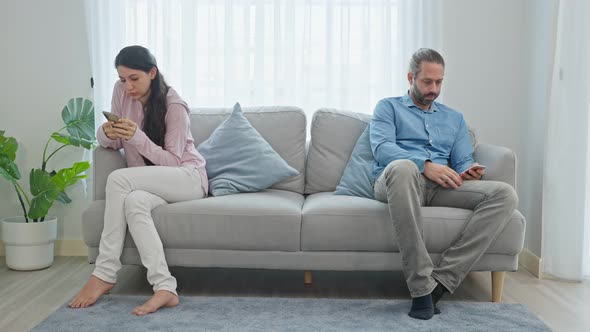 Family problem, Caucasian phone addict couple don't pay attention to each other while sit on sofa. alt