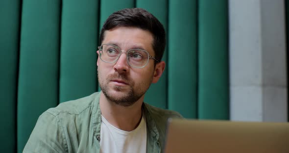 Man Sits in Cafe in Daytime and Using the Laptop for the Remote Work alt