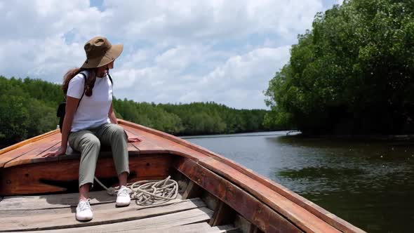 A woman sitting on a long tail boat while traveling the mangrove forest