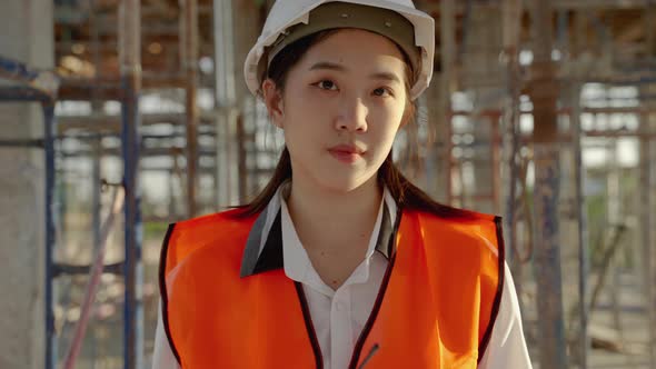 Portrait, young Asian female engineer standing proudly smiling at her work site.