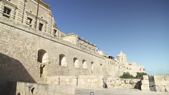 Mdina City Walls with Malta Flag Waving in Wind on a Sunny Day