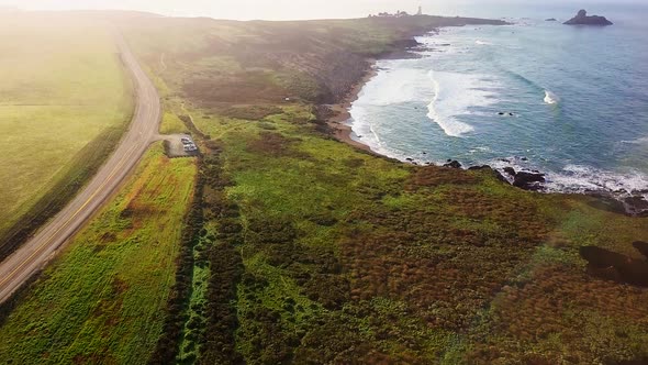 Aerial reveal of beach and highway at Peidras Blancas Lighthouse in California alt