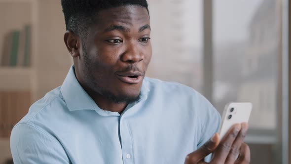 African American Surprised Man Millennial 30s Businessman Employee Owner Hold Mobile Gadget Modern alt