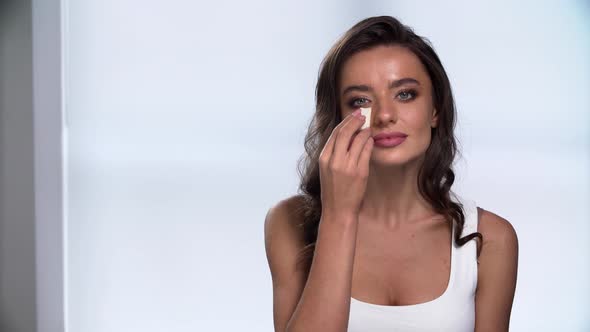 Makeup. Beautiful Woman Applying Foundation On Face With Sponge alt