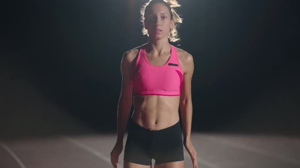 A Young Girl is Standing Alone at the Track and Field Stadium and is Preparing for the Race alt