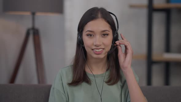 Web Camera POV of Young Beautiful Asian Woman Turning on Earphones Waving and Smiling alt