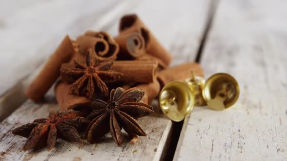 Star anise, cinnamon and small bells on a plank alt