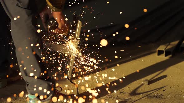 Worker's Hands Hold a Working Angle Grinder