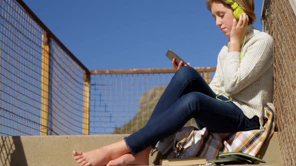 Girl taking selfie with mobile phone near beach alt